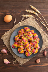 Rainbow colored dumplings with microgreen on brown wooden. Top view, flat lay