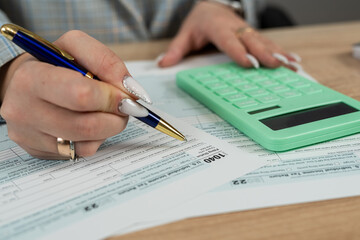 Business woman filling  individual income tax return form, tax documents in office