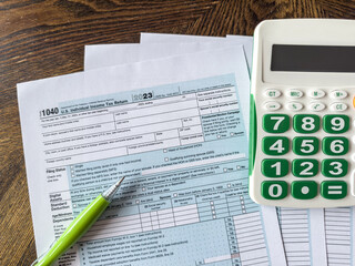 2023 tax return form 1040 with pen and calculator on desk