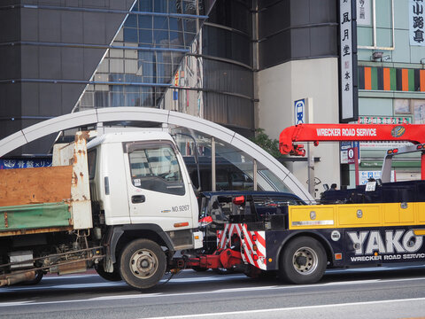 TOKYO, JAPAN - February 8, 2024: An Isuzu Forward truck being pulled by a tow truck in Tokyo's Ueno area.