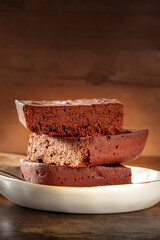 Chocolate brownie, simple coffee cake, a side view shot on a dark rustic wooden background with a place for text