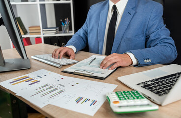 Business man in suit calculate annual profit by duty with finance document computrer and calculator