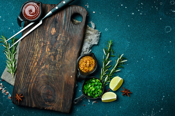 Kitchen cutting board on table with spices, vegetables and herbs. Free space for a recipe. Rustic...