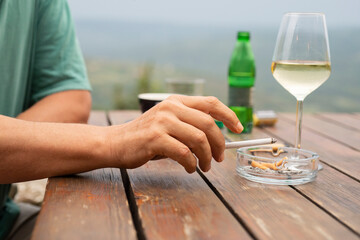 A man's hand is holding a cigarette between his two fingers
