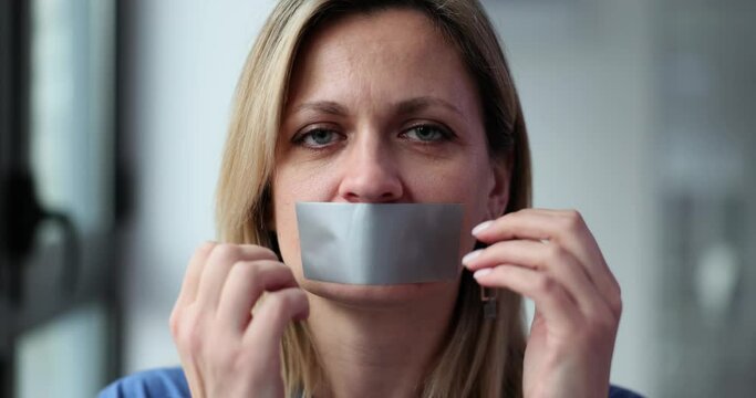 Adult blonde woman smilingly sticks tape on face covering mouth