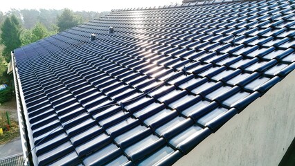 Dach, dachówka na budynku jednorodzinnym, zdjęcie pod słońce z drona.