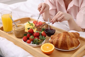 Woman having tasty breakfast on bed, closeup