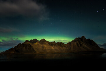 Aurora Borealis über imposanten Gebirgszügen unter Sternenhimmel