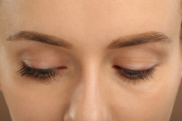 Woman showing difference in eyelashes length after mascara applying, closeup