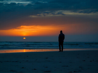 person walking on the beach at sunset