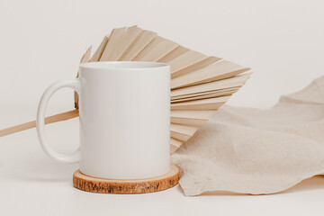 White mockup mug on wooden cup coaster with palm leaf and linen cloth. Mockup mug for logo,...