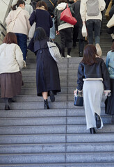 駅のホームの階段を登る若い女性たちの後ろ姿