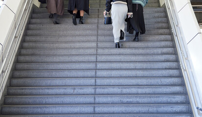 駅のホームの階段を登る若い女性たちの後ろ姿
