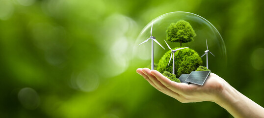 Fototapeta na wymiar Business hand holds green globe with tree, wind turbine and solar powered for ESG, CO2 and Net Zero concept for sustainable corporate environmental development. Save the environment.