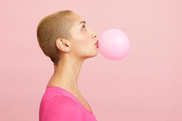 Young blond woman blowing pink balloon 