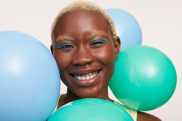 Portrait of smiling woman with short white hair and balloons