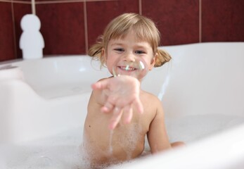 Smiling girl showing bubble in bathtub at home, selective focus