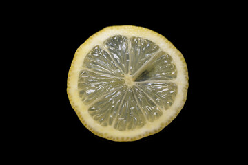 Yellow lemon slice with dark black background horizontally overhead Citrus aurantifolia