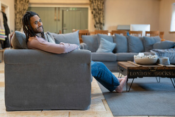 Man with dreads talking relaxing on sofa in cozy living room