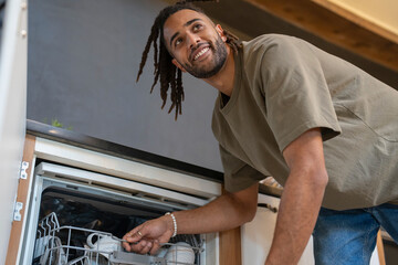 Man with dreads loading dishwasher