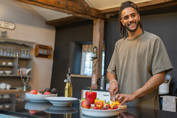 Men with dreads cutting vegetables in kitchen