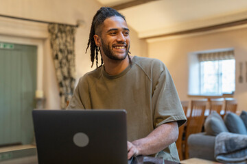 Man with dreads working on laptop at home