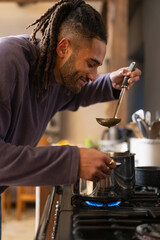 Man tastes food from pot in kitchen 