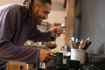 Smiling man holds stew in ladle 