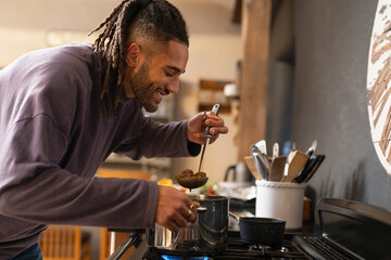 Smiling man holds stew in ladle 