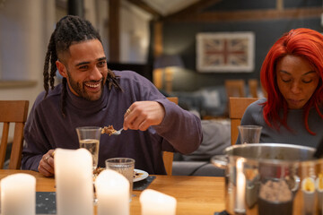 Smiling man eating dinner with friends