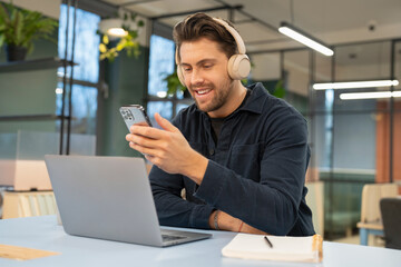 Naklejka na ściany i meble Businessman using phone and laptop in modern office