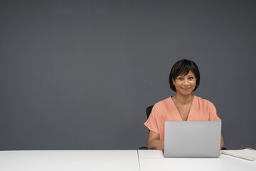 Portrait of smiling mature businesswoman working on laptop in office