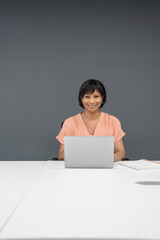 Portrait of smiling mature businesswoman working on laptop in office