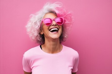 Portrait of a happy woman with pink hair and sunglasses over pink background