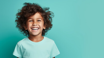 Joyful child laughing with curly hair on teal background