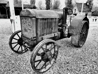 Black and white photo of a Rusty vintage tractor with metal wheels and seat
