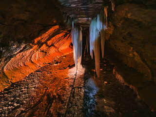  The illuminated frozen waterfall of underground waters under the arches of a man-made industrial...