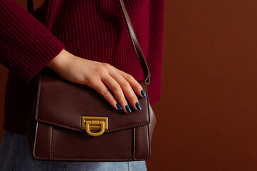 Close up photo of trendy brown leather shoulder bag, purse in fashionable outfit. Woman wearing...