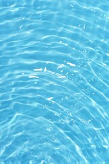 Water surface. Bluewater waves on the surface ripples blurred. Defocus blurred transparent blue colored clear calm water surface texture with splash and bubbles. Water waves with shining pattern.
