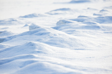 Fototapeta na wymiar Wavy snowdrift surface on a sunny day, natural background