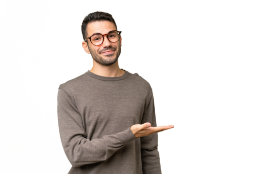 Young handsome caucasian man over isolated background presenting an idea while looking smiling towards