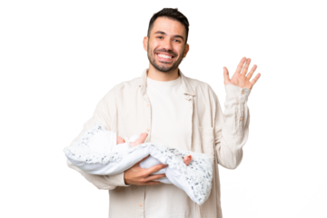 Young caucasian father with her newborn baby over isolated background saluting with hand with happy expression