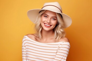 young beautiful smiling blonde woman in fashionable summer clothes and hat. carefree woman posing near a yellow wall in the studio.
