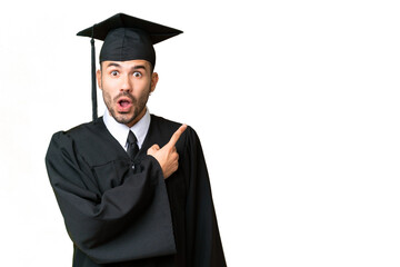 Young university graduate man over isolated chroma key background surprised and pointing side