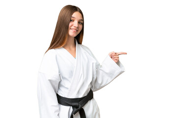 Teenager girl doing karate over isolated chroma key background pointing finger to the side