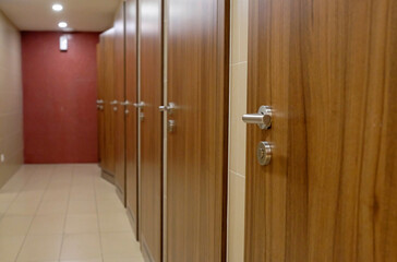 Multiple stalls with wooden doors in a row in a bathroom