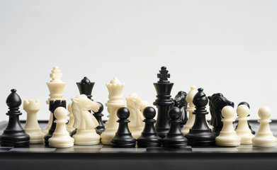White and black chess include king queen horse ship and pawn on chessboard.
