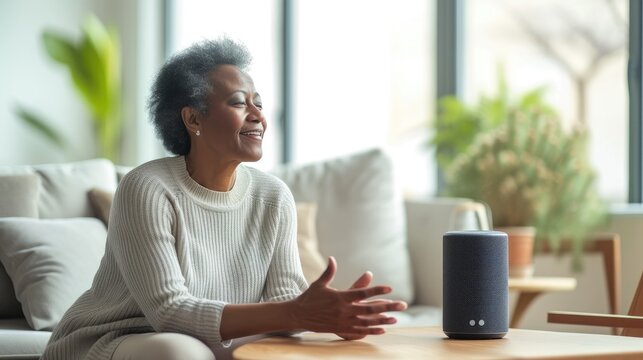  Senior woman using voice controlled smart speaker and personal asistent, smart device concept, technologies, gadget, background minimalistic. Concept of Smart Home and Automation