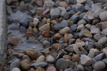 Macro of pile of multicoloured rocks with small puddle