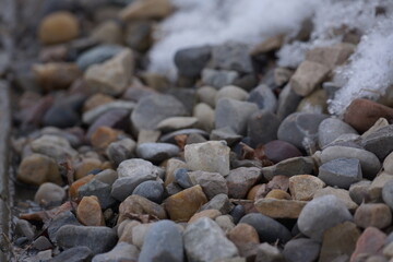 Multicoloured pebbles with patch of snow on it, macro